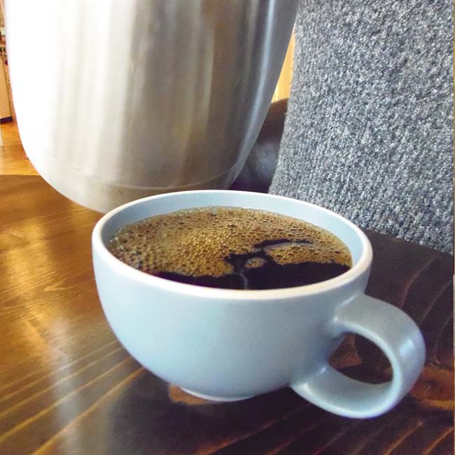 Coffee in a cup with a lot of bubbles on top.