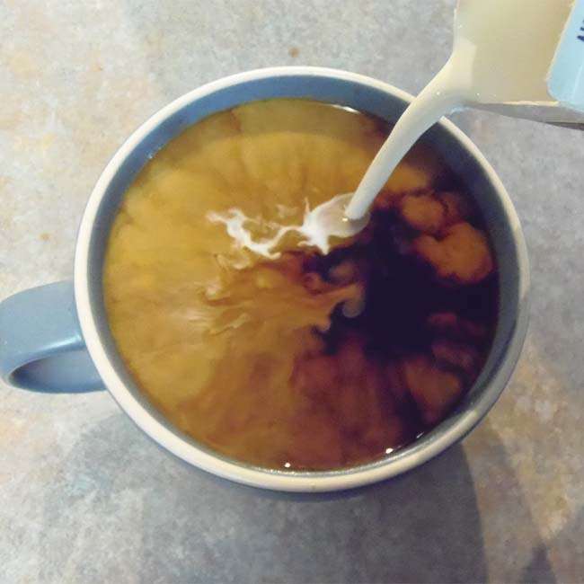Cream being poured into a coffee cup.
